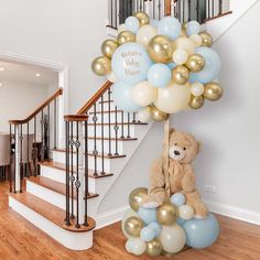 a teddy bear sitting on top of a bunch of balloons in front of a staircase