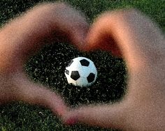 a soccer ball in the shape of a heart is being held by someone's hands