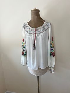 A vintage embroidered folk blouse. It has multicoloured tassels and floral embroidery. Finished with French seams. The embroidery has some colour run. UK Size 8 - 10. Please check measurements: Chest - 108cm Waist - 102cm Length - 56cm Bohemian Peasant Top With Multicolor Embroidery, Spring Folk Embroidered Peasant Top, Spring Bohemian Embroidered Peasant Top, Bohemian Embroidered Peasant Top For Spring, Bohemian Embroidered Peasant Top For Fall, Spring Multicolor Embroidered Peasant Top, Bohemian Floral Embroidered Peasant Top For Festivals, Spring Peasant Top With Multicolor Geometric Embroidery, Folk Style Peasant Top With Floral Embroidery For Spring