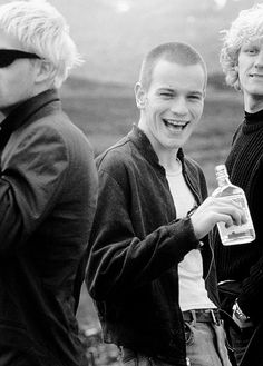 three young men standing next to each other with one holding a bottle in his hand