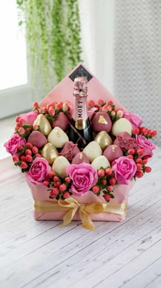 pink roses and chocolates in a heart shaped gift box with champagne bottle on top