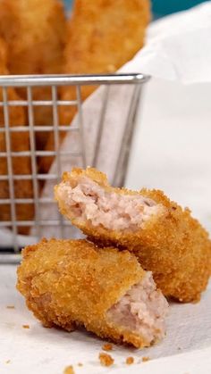 some fried food is in a basket and on the table next to it are chicken nuggets