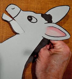 a person cutting out a paper animal with scissors and glue on the back of it