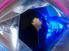 a blue bottle with gold flakes in it sitting on top of some plastic bags