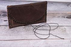 a brown leather wallet sitting on top of a white wooden floor next to a string