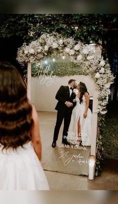 a bride and groom kissing in front of a wedding photo