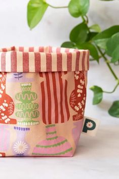 a pink and red striped bag sitting on top of a table next to a potted plant