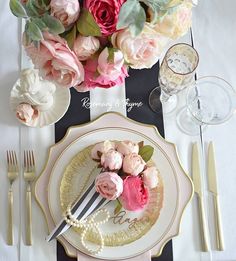 there is a plate with flowers on it next to silverware and wineglasses