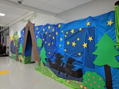 a classroom hallway decorated in blue and green with paper cutouts on the walls, trees, and people