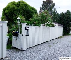 a white picket fence next to a gravel road