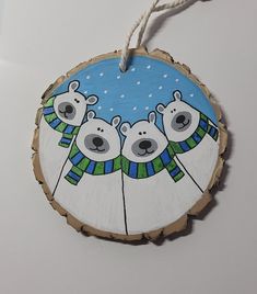 a wooden ornament with three polar bears wearing sweaters on it's side