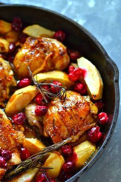 a skillet filled with chicken, apples and cranberries