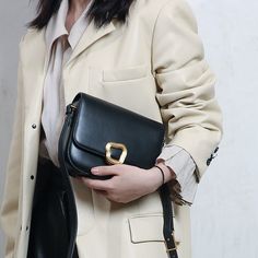 a woman holding a black purse in her hands