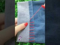 someone is stitching something with red thread on the side of a piece of fabric