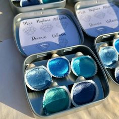 four tins filled with blue and green colored pastries sitting on top of a table