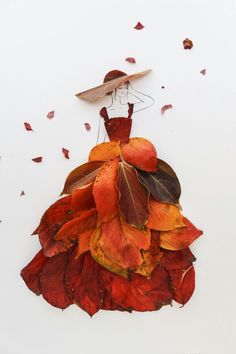 a dress made out of leaves with a hat on the top and red petals around it