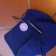 a pair of scissors sitting on top of a blue knitted cloth