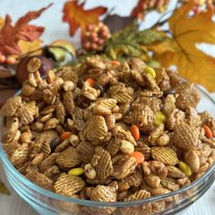 a glass bowl filled with nuts and candy cornflakes on top of a table