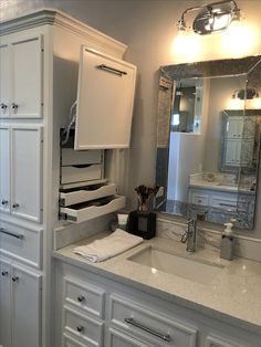 a bathroom with white cabinetry and marble counter tops, along with a large mirror above the sink