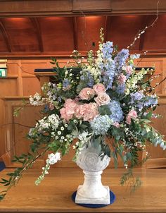 a white vase filled with lots of flowers on top of a table