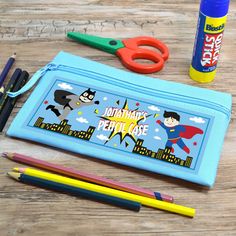 This personalised blue pencil case for boyscomes with enough storage for pencils, pens and all other stationary items your kid needs for writing. With a big zip on top and a blue polyester material so that dirt can't be seen as easily and washed off quickly as well. It got a cute superhero design in comic style with a city background on the front. Customise this pouch with a name or message- pick from many different fonts to match your own style and create a truly unique gift. For in between pre Educational Blue Stationery For School, Blue Educational Stationery For School, Educational Blue Pencil Case With Pen Holders, Blue Pencil Case For Back To School, Blue Rectangular Educational Pencil Case, Blue Rectangular Pencil Case, Educational Blue Pencil Case Gift, Blue Pencil Case, Blue Superhero