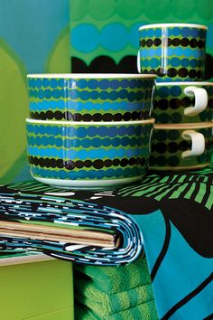 three cups and two napkins sitting on top of a green table cloth next to each other