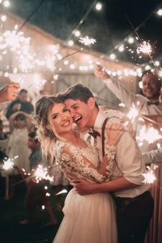 a bride and groom hugging while holding sparklers