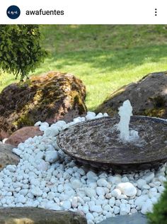 a water fountain surrounded by rocks and grass