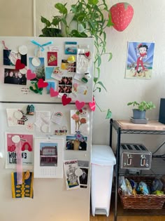 a refrigerator covered in magnets and pictures next to a potted plant