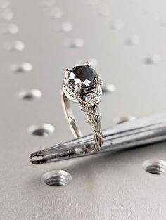 a black diamond ring sitting on top of a silver pen with drops of water around it