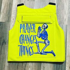 a yellow vest with a skeleton on it and blue writing that says prayer, change, things