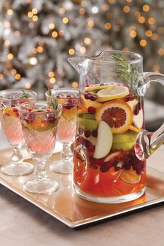 a pitcher and glasses filled with fruit on a tray