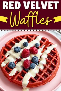 red velvet waffles are topped with berries and drizzled with cream