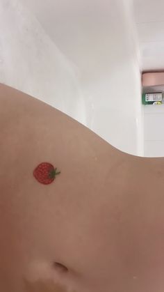 a small strawberry on the back of a man's stomach in a bath room