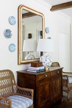 a living room with wicker chairs and a table in front of a large mirror