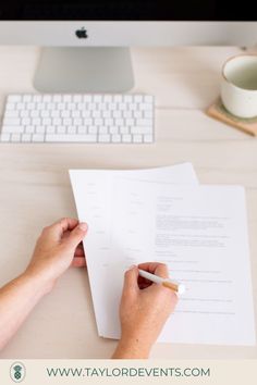 a person writing on a piece of paper next to a computer