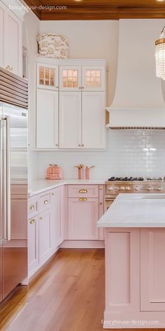 a pink kitchen with white cabinets and wood floors is featured in this image from the front view