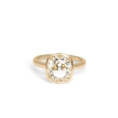 a gold ring with an oval cut diamond in the center, on a white background