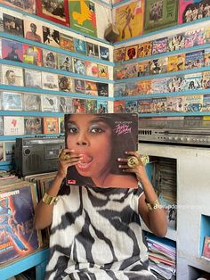 a woman holding up a record in front of her face and surrounded by records on the wall