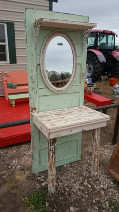 an old door with a mirror on it sitting in front of a red bench and tractor