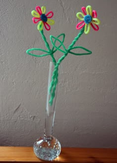 a glass vase filled with flowers on top of a wooden table next to a wall