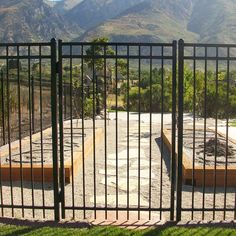 an iron gate is open to reveal a skateboard park in the distance, with mountains in the background