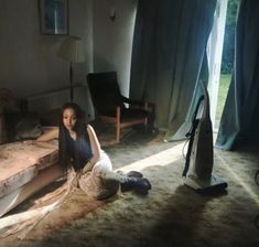 a woman sitting on the floor next to a couch