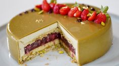 a chocolate cake with strawberries and pistachios on top, cut in half