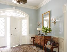 a room with blue walls and white trim, an ornate mirror on the wall, a wooden bench in front of it