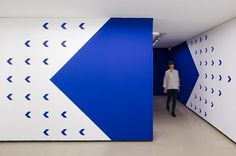 a man is walking through a blue and white room with arrows painted on the walls