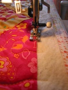 the sewing machine is sitting on top of the quilts and tablecloth with colorful designs