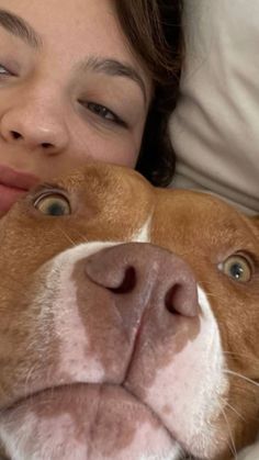 a woman is laying in bed with her pitbull dog and smiling at the camera