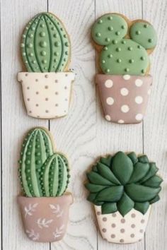 four decorated cactus and succulent cookies sitting on top of a wooden table next to each other