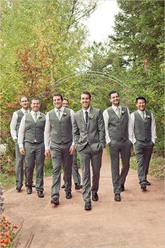 a group of men in suits and ties walking down a dirt road next to trees